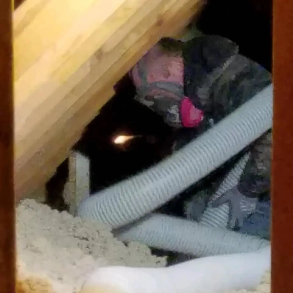 Crew member in a respirator working in an attic